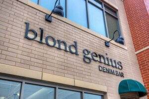 blond genius denim bar sign on exterior of brick building